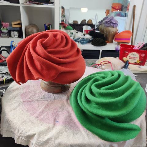 Red and green felt hand-swirled hats on a table