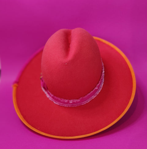 Lina Stein Millinery Red cowboy hat with a purple band on a pink background